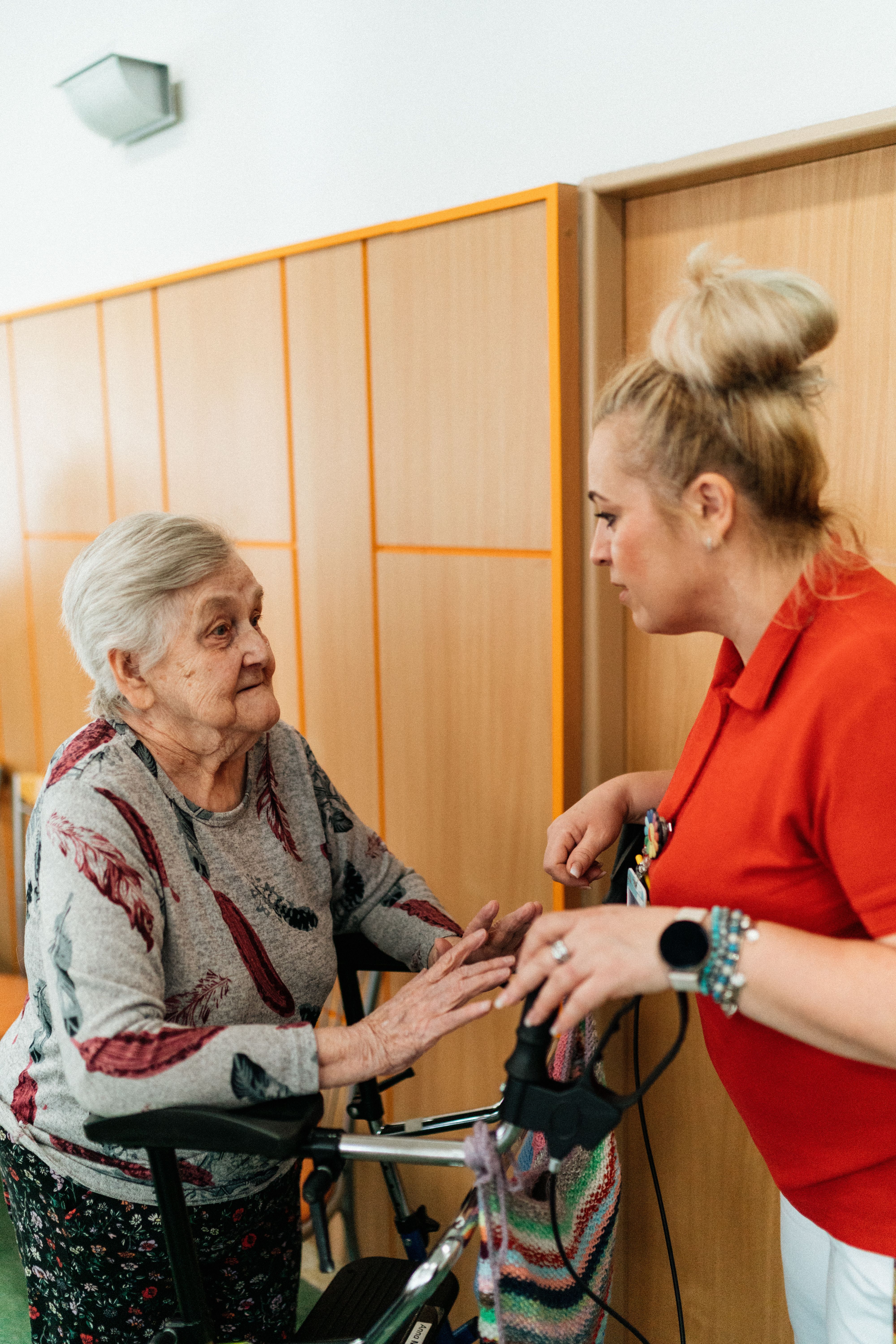 Cuidadora conversando com atenção e carinho com uma senhora idosa em um corredor de casa